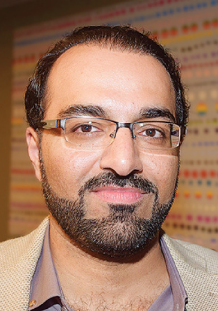 man smiling at camera with glasses and beige background
