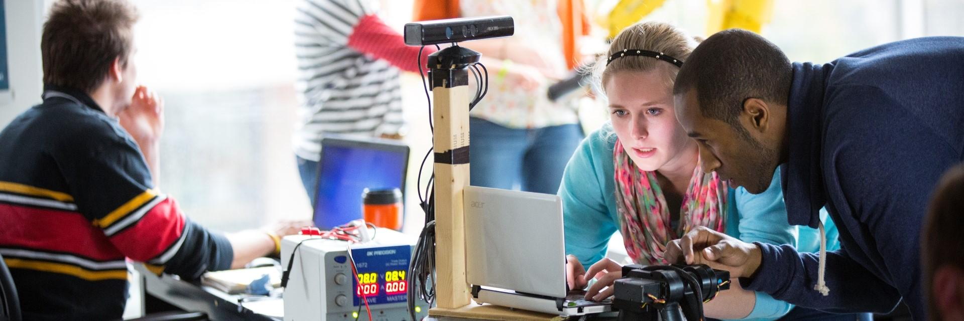 three people working with computers and robotics