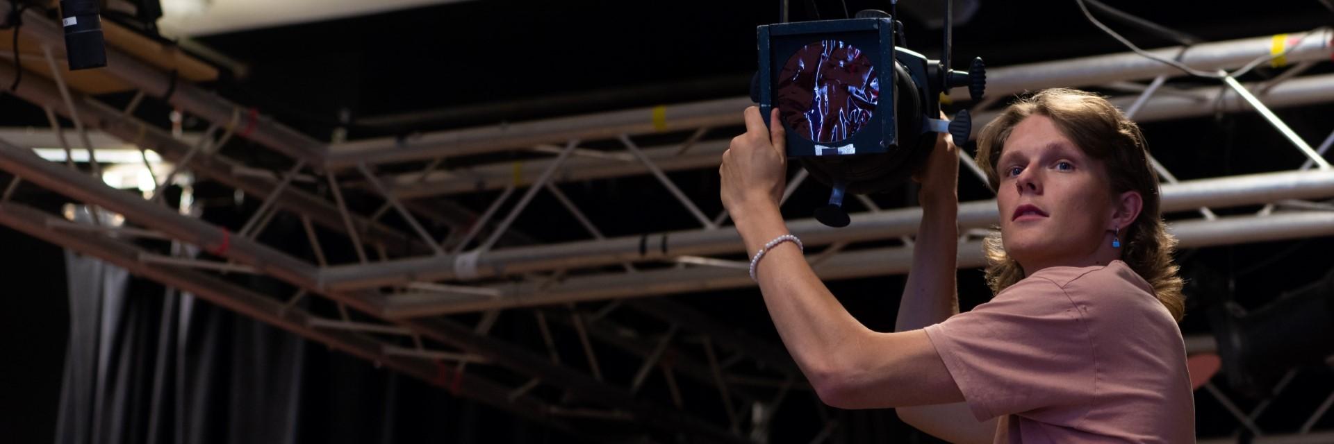 person adjusting stage spotlight