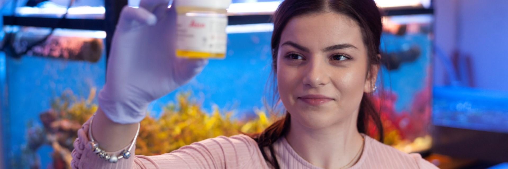 person in front of aquarium holding sample