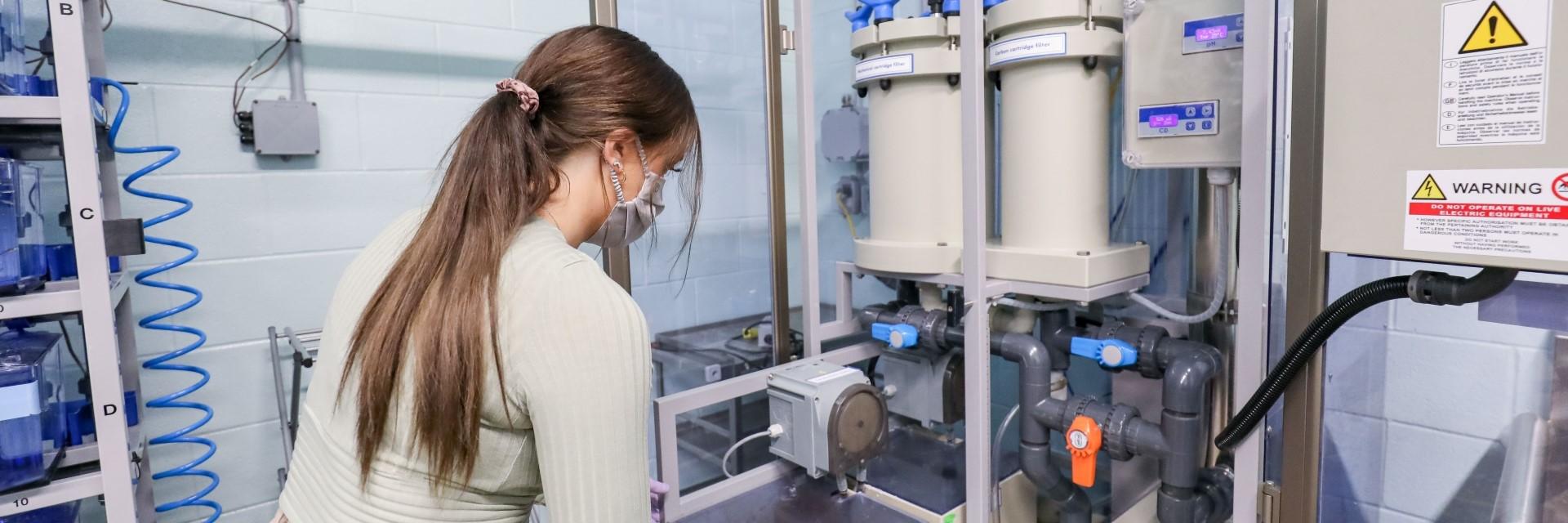 Person wearing a medical mask works in a water lab setting.