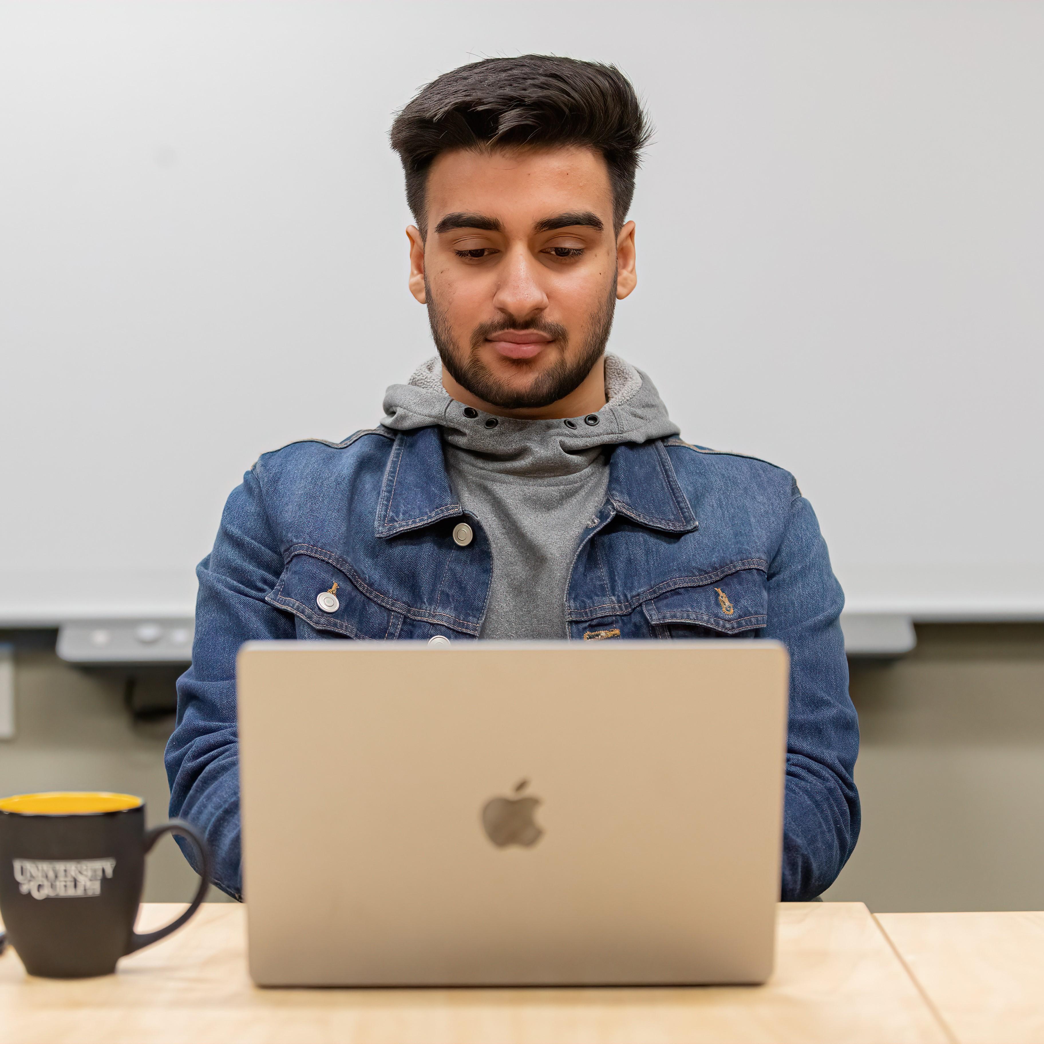 person sits at a table focusing on a laptop computer