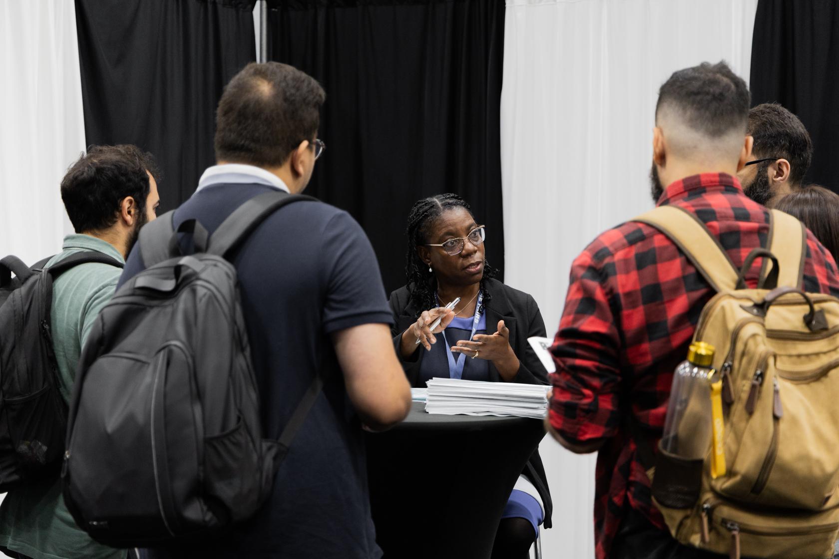 A career advisor gives advice to a group of students at a job fair.