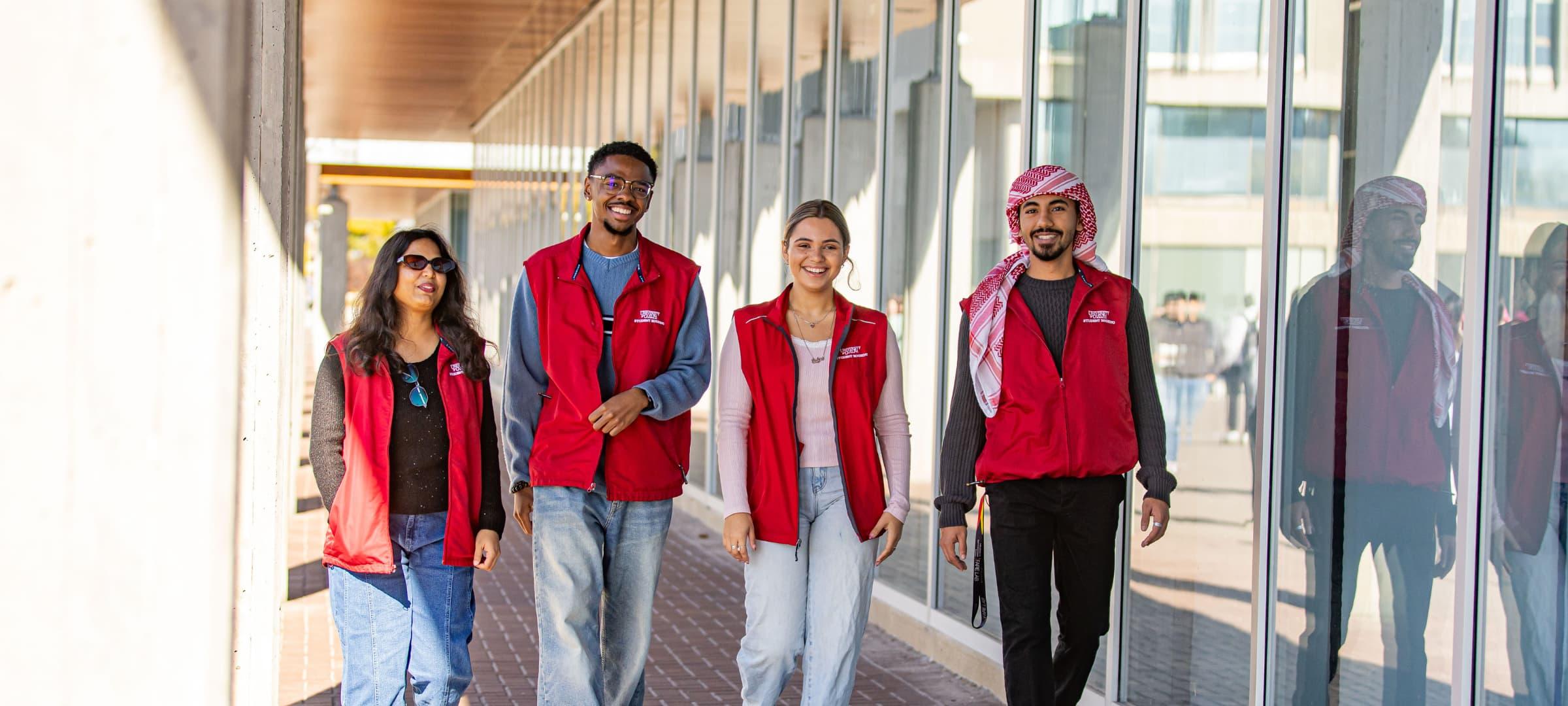 Four Residence Life Staff member walking outside engineering building on campus