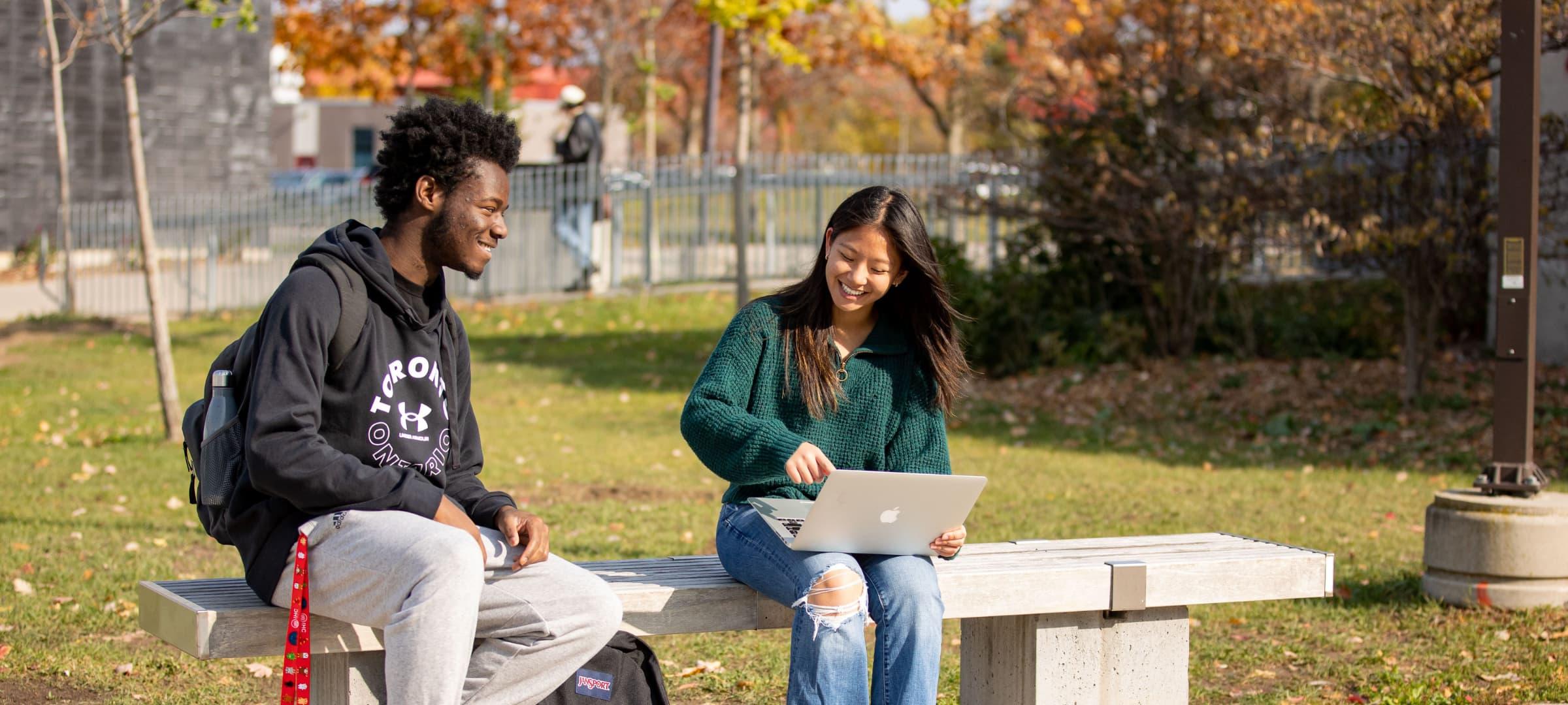 Two Students sitting on bench outside South Residence