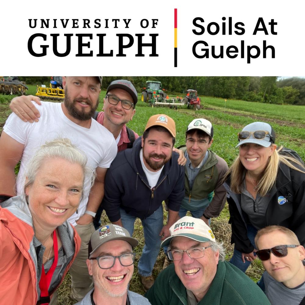 Group of eight individuals smiling in a field, with farming equipment in the background. The image includes a logo of the University of Guelph and the text "Soils At Guelph.