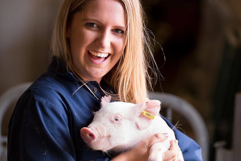 A woman holding a baby pig in her arms