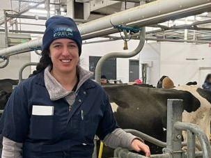 Anna Schwanke is in a dairy barn wearing work coverall and a toque