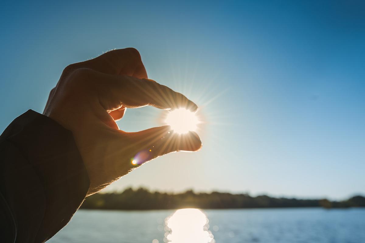 Hands holding the sun by the fingers