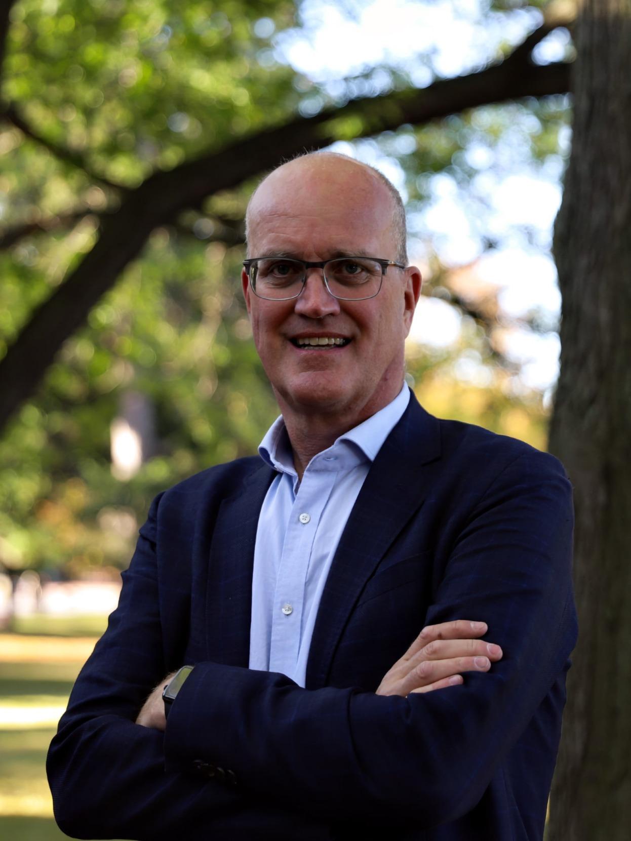 Von Massow stands outside, arms crossed, in a suit jacket in this portrait photo