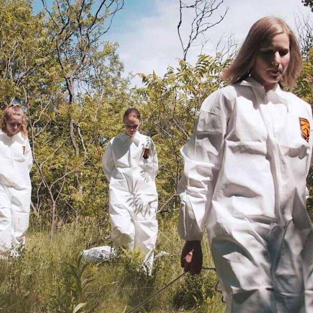 Three woman in white jump suits walking through a field