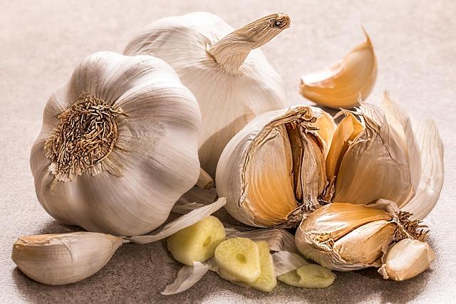 Close-up of two whole heads of garlic and one head broken apart into cloves