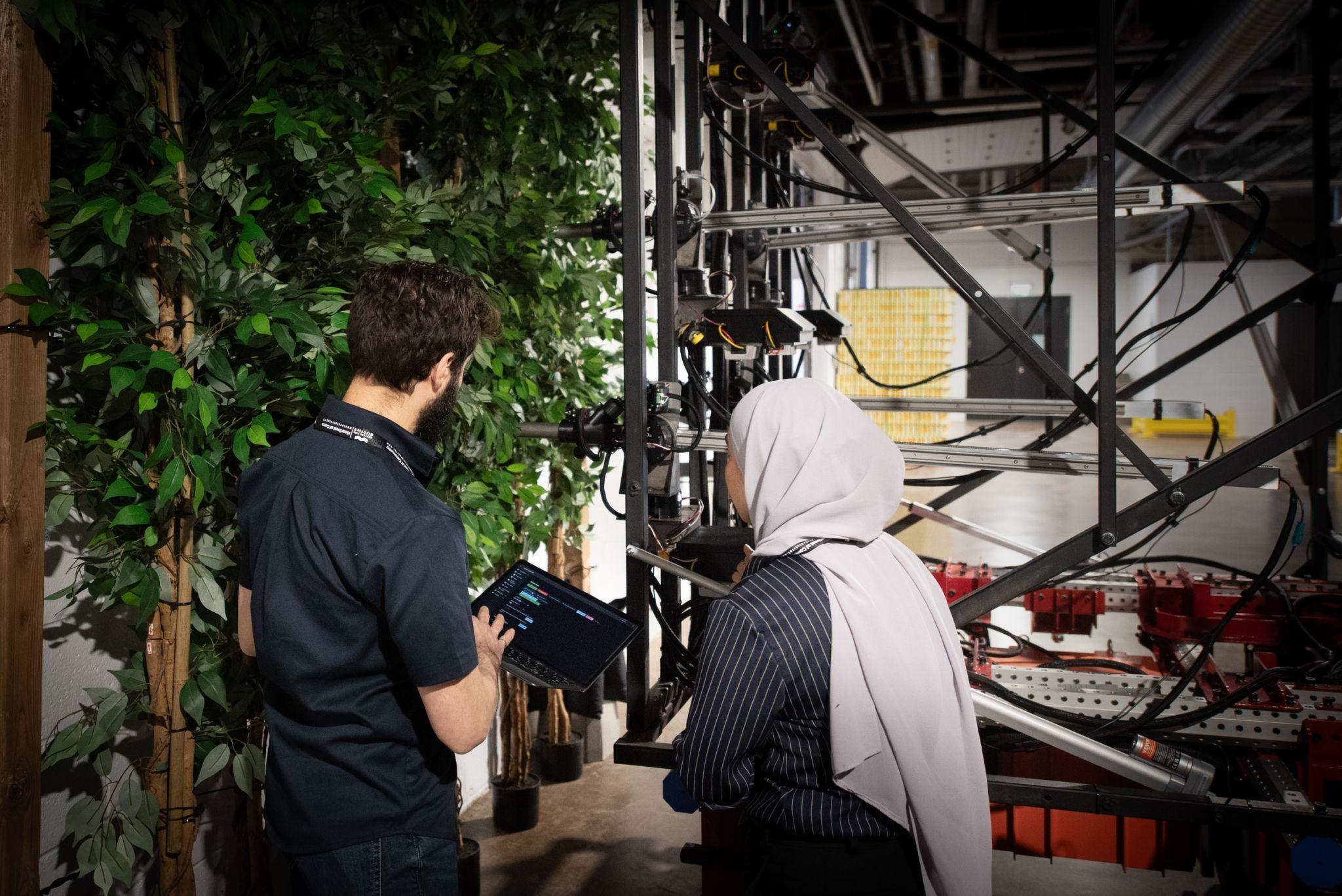 One person demonstrating an ag robot to another person.