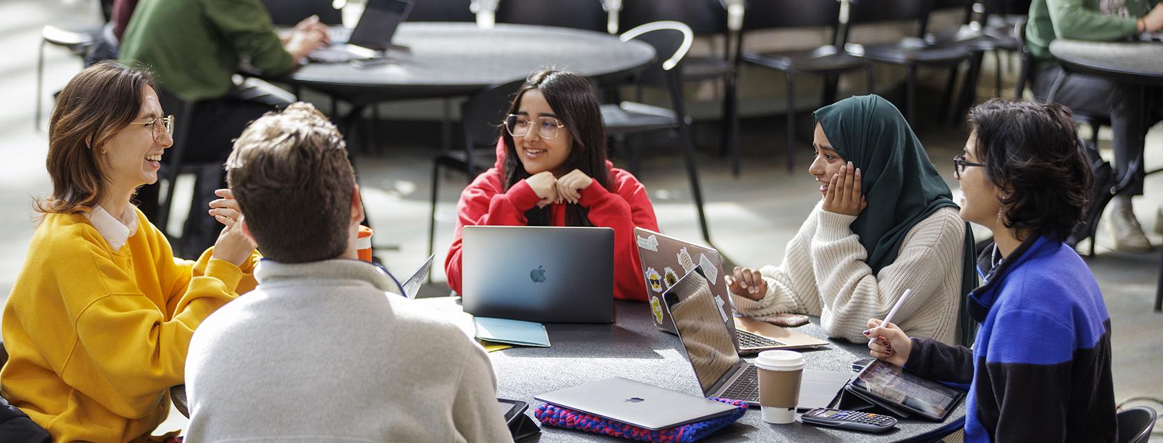 Group of students sitting around a table talking.