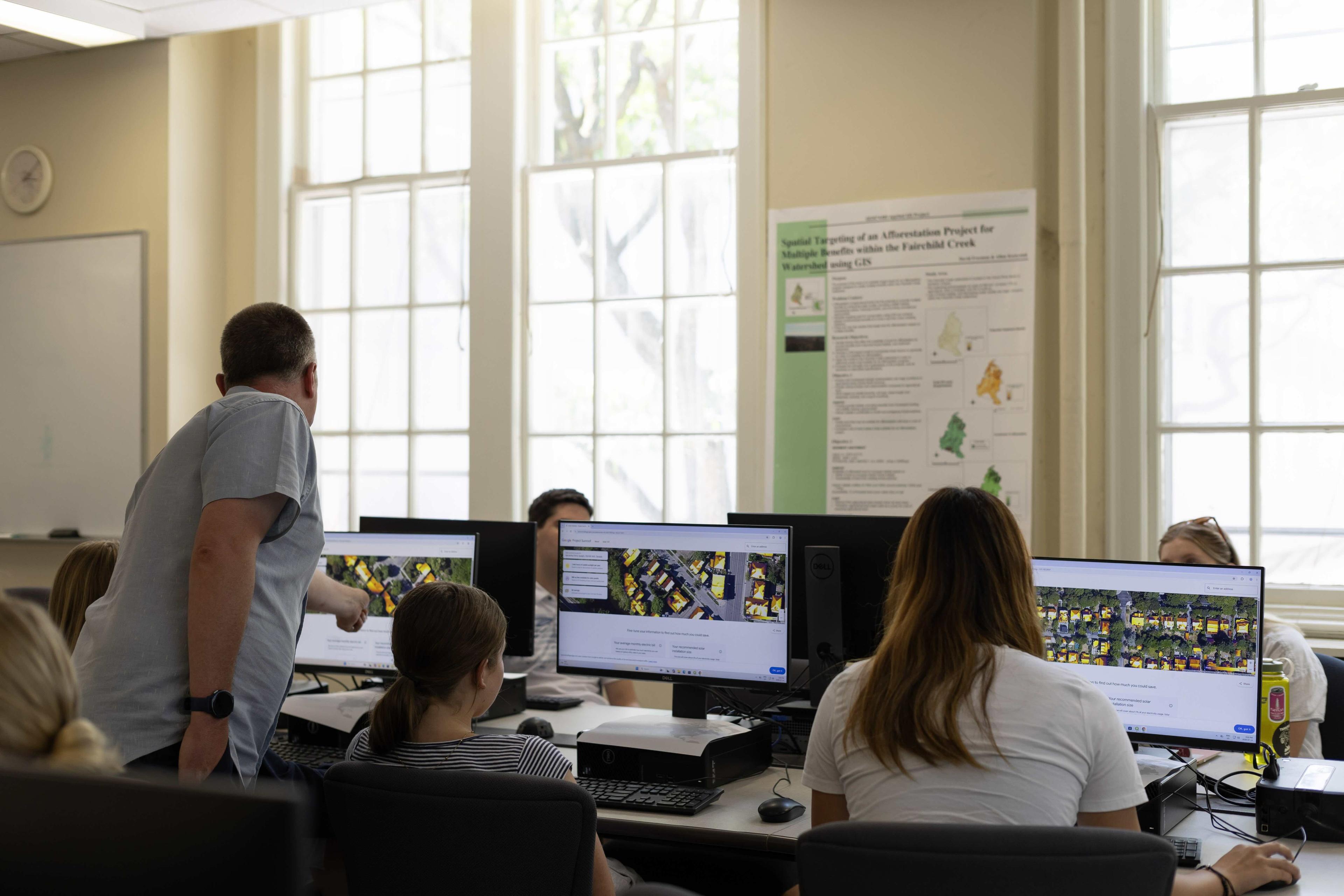 Career Camp students working in a computer lab with instructor pointing to the screen assisting one student
