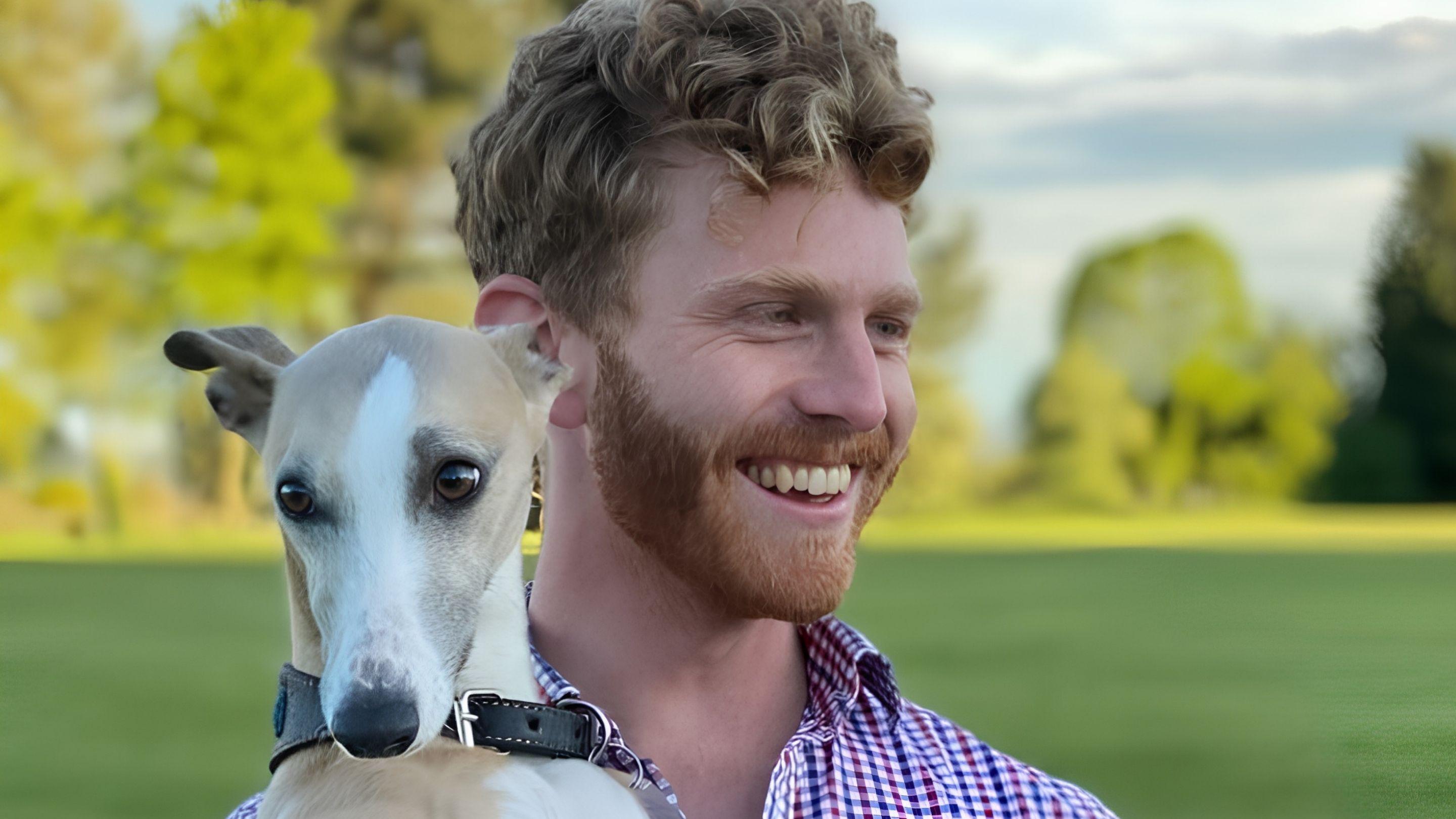 caucasian man with strawberry blonde curly hair holding an italian greyhound dog