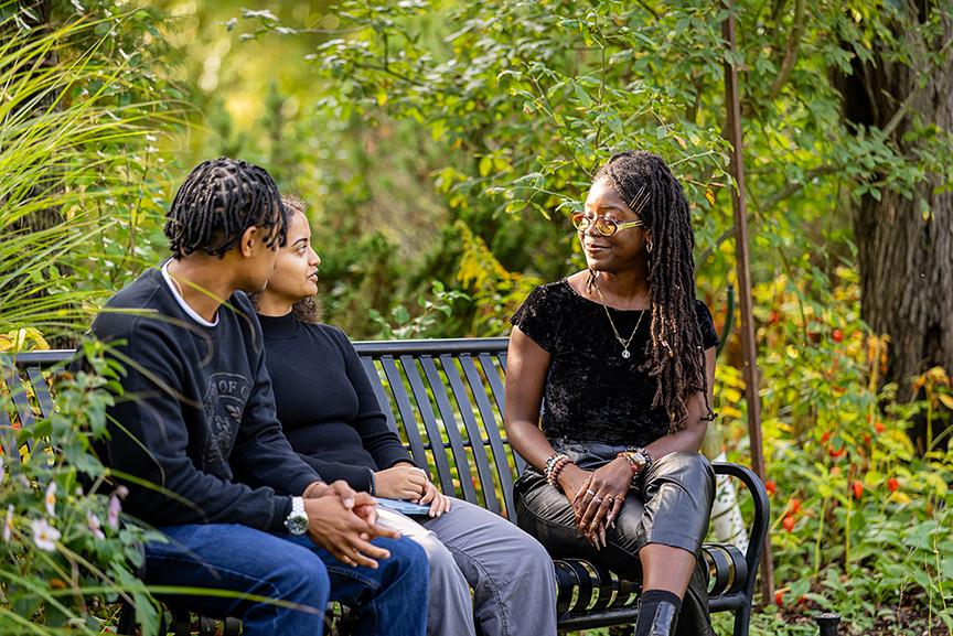Black and racialized mentor and two mentees talking at a bench