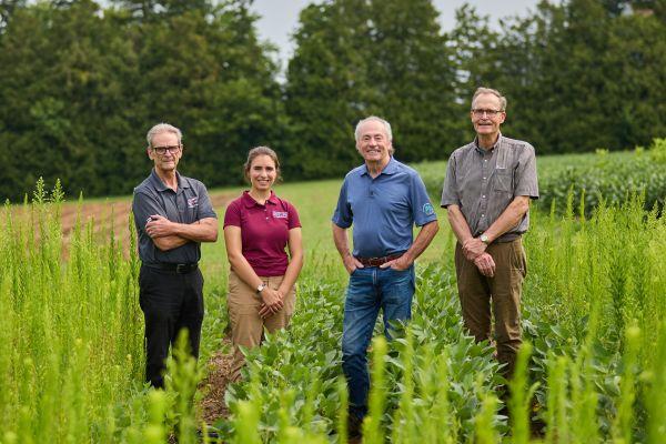 Peter Sikkema and Isabella Aicklen stand with industry partners in a field