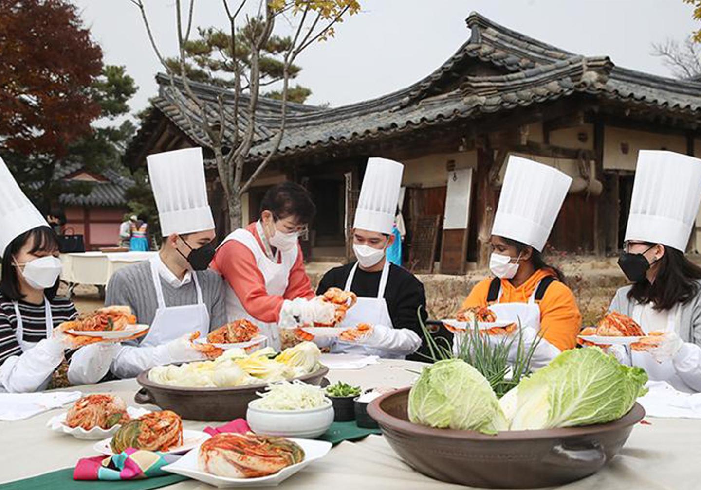 People holding food around a table at a cooking school